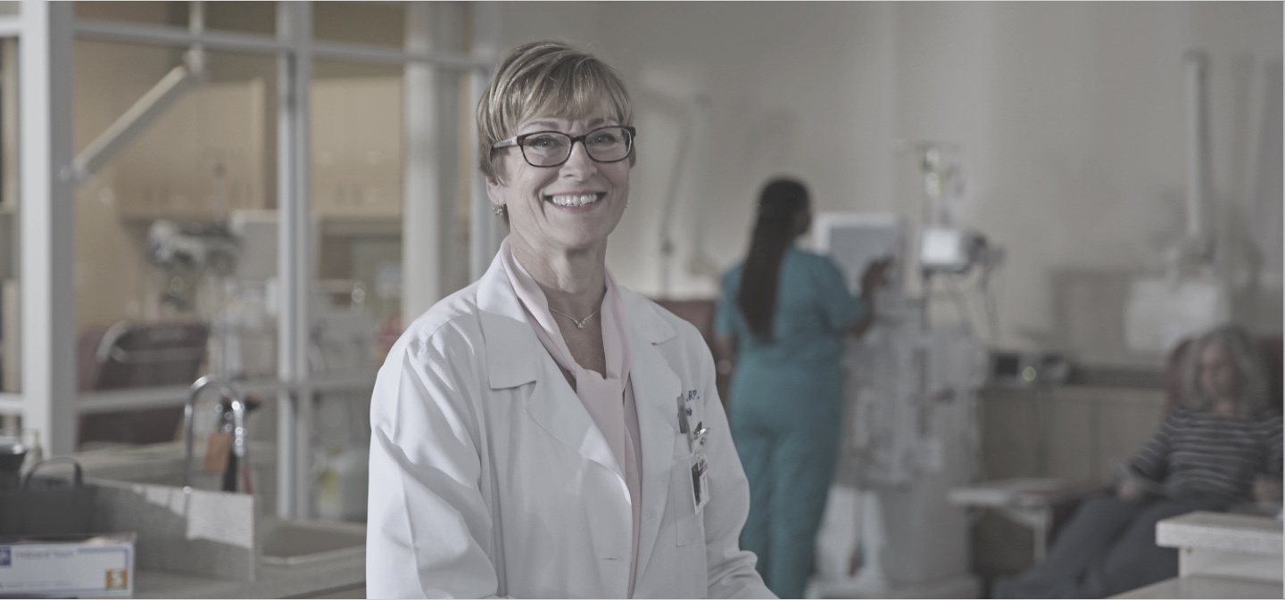 Image of Debbie Glidden standing at a nurses' station in a dialysis organization