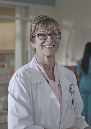 Image of Debbie Glidden standing at a nurses' station in a dialysis organization